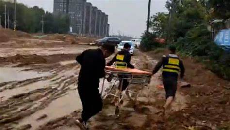 医护人员抬担架穿越泥泞道路，担架缝隙渗出血迹